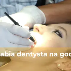 Dentysta w białej rękawiczce wykonuje zabieg na zębach pacjentki.